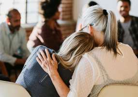 women hugging during epilepsy and suicide support group